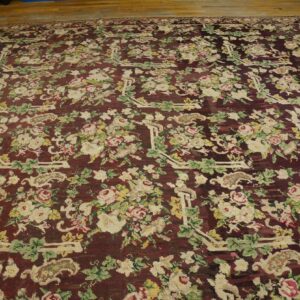 Close-up of a deep burgundy rug with a dense floral pattern featuring cream and pink roses and green leaves, by Rugs On Net