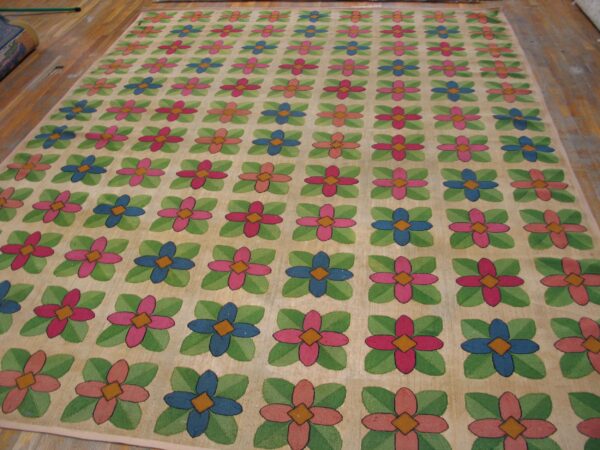 A brightly colored rug featuring a repeating grid pattern of stylized four-petal flowers in pink and blue, surrounded by green leaves, all set against a light beige background. This is the floral grid rug by rugs on net. By rugs on net