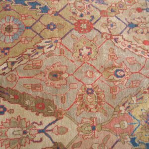 Close-up of an antique rug with geometric and floral motifs in muted gold, red, and blue tones by Rugs On Net. by Rugs On Net