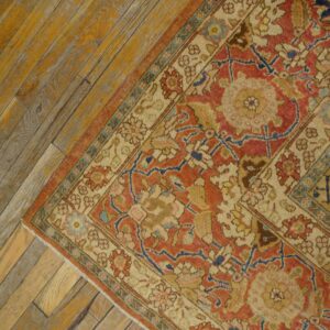 Close-up corner of an antique rug with red and beige patterns on distressed wood flooring by Rugs On Net
