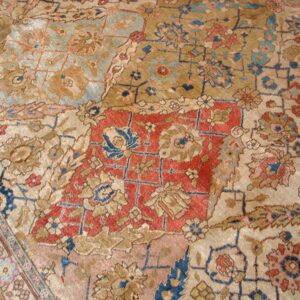 Close-up of faded, antique rug with geometric and floral patterns in muted reds, blues, and tans, by Rugs On Net