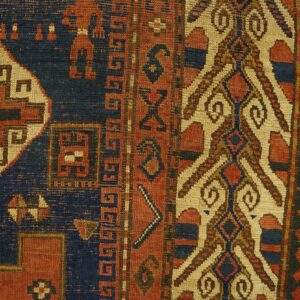 Close-up detail of an antique rug showing geometric patterns in red, navy blue, and cream, by Rugs On Net