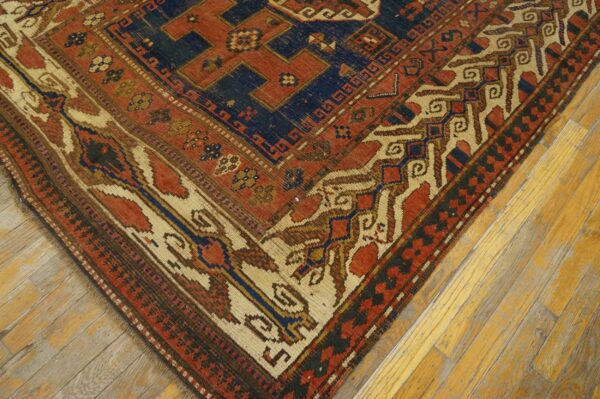 Close-up corner detail of an antique rug featuring geometric patterns in red, navy blue, and cream, by rugs on net. By rugs on net