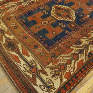 Close-up of a richly colored antique rug with geometric patterns in red, blue, and cream on a wooden floor, by Rugs On Net