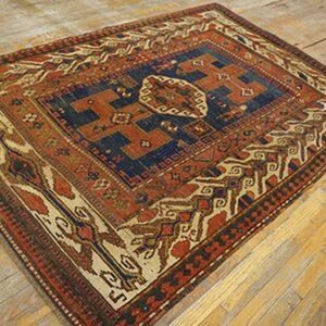 Antique rug with deep blue and rust colors on a wooden floor by Rugs On Net