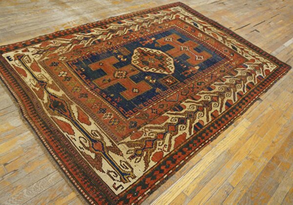 Antique rug with deep blue and rust colors on a wooden floor by rugs on net