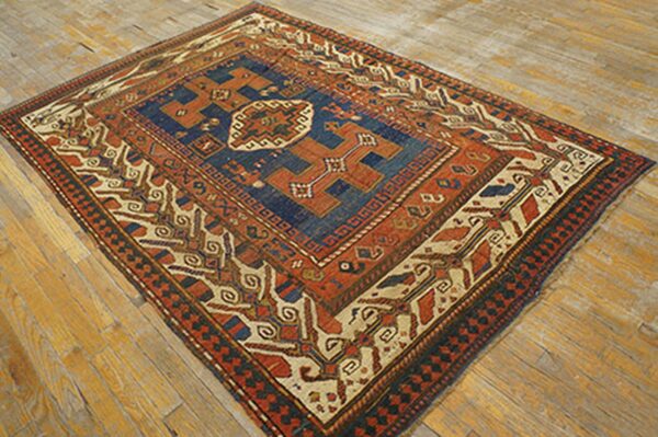 An antique rug with bold geometric patterns in red, blue, and cream on a wooden floor by rugs on net. By rugs on net