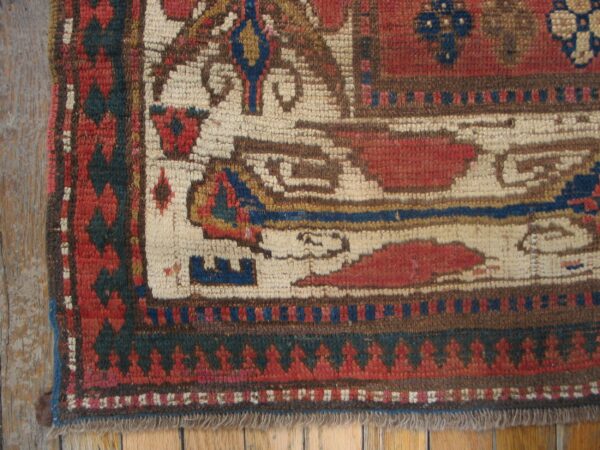 Close-up of an antique tribal rug border with geometric patterns in red, cream, and blue by rugs on net