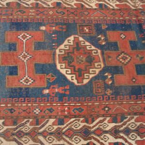 Close-up of a vintage red and blue Caucasian rug with geometric motifs by Rugs On Net