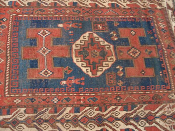 Close-up of a vintage red and blue caucasian rug with geometric motifs by rugs on net
