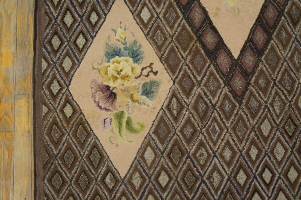 Close-up of a hooked rug featuring a central floral medallion surrounded by a brown diamond lattice pattern, by rugs on net. By rugs on net