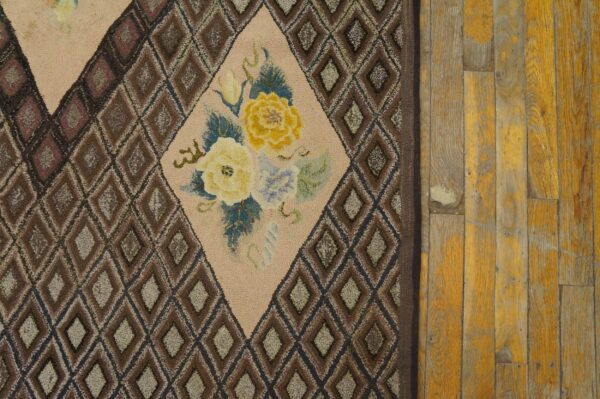 Close-up of a hooked rug with brown diamond patterns and a central floral medallion featuring yellow roses, by rugs on net. By rugs on net