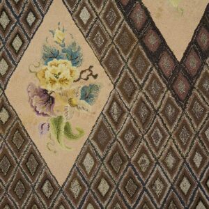 Close-up of a hooked rug featuring brown diamond patterns and a central beige medallion with yellow and purple flowers, by Rugs On Net