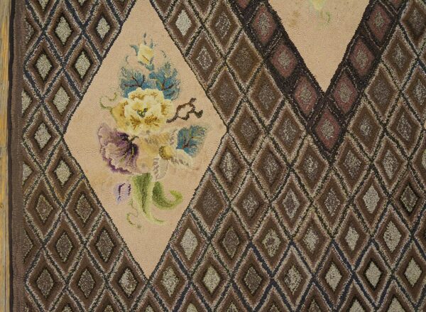 Close-up of a hooked rug featuring brown diamond patterns and a central beige medallion with yellow and purple flowers, by rugs on net
