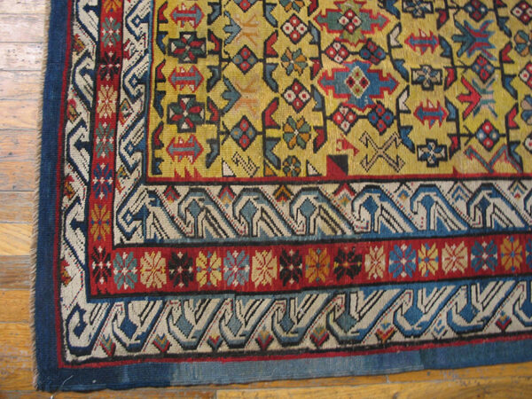 Close-up of the corner of a vibrant yellow field rug with geometric borders by rugs on net. By rugs on net