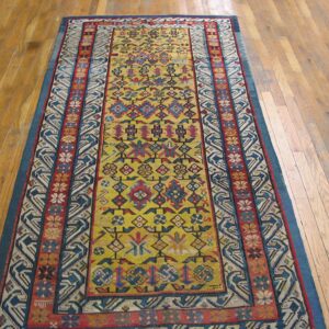 A long runner rug with a vibrant yellow field and geometric patterns in red and blue on a light wood floor by Rugs On Net. by Rugs On Net