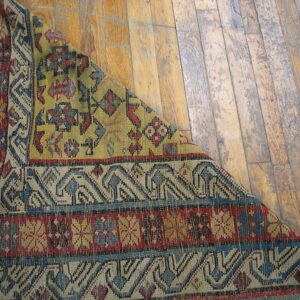 Close-up detail of a colorful antique rug corner on a wooden floor by Rugs On Net