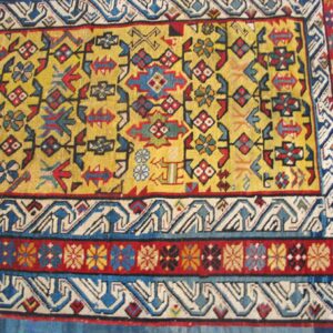 Close-up of a vibrant yellow field rug with geometric and floral motifs, bordered by intricate blue and white patterns by Rugs On Net. by Rugs On Net