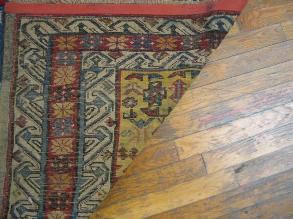 Close-up of a colorful geometric rug partially rolled back on a wooden floor, by rugs on net