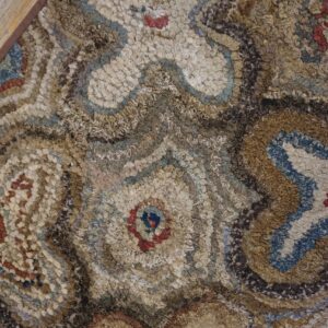Close-up texture of a multicolored hooked rug with abstract, swirling patterns in beige, brown, and blue, by Rugs On Net