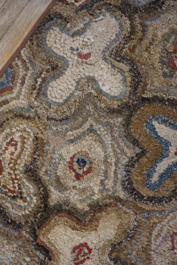 Close-up texture of a multicolored hooked rug with abstract, swirling patterns in beige, brown, and blue, by rugs on net