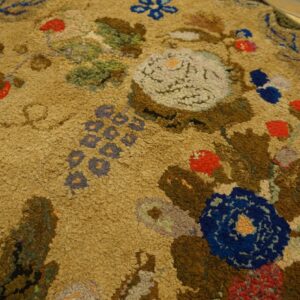 Close-up of a hooked rug with floral motifs in brown, blue, and red on a tan ground by Rugs On Net. by Rugs On Net
