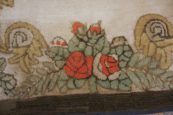 Close-up of a hooked rug featuring vibrant red roses and green foliage against a light background, by rugs on net. By rugs on net