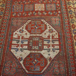 Close-up of a richly patterned, antique red and blue rug, featuring geometric medallions and border details by Rugs On Net. by Rugs On Net