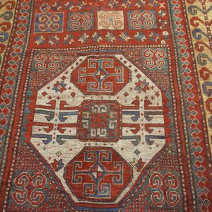 Close-up of a richly patterned antique rug featuring central geometric medallions in red, cream, and blue, by Rugs On Net
