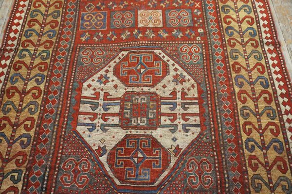 Close-up of a richly patterned antique rug featuring central geometric medallions in red, cream, and blue, by rugs on net