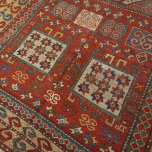 Close-up of a richly colored, geometric patterned rug featuring red, blue, and cream accents by Rugs On Net. by Rugs On Net