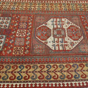 Close-up of a richly colored antique rug featuring geometric motifs in red, blue, and cream by Rugs On Net. by Rugs On Net