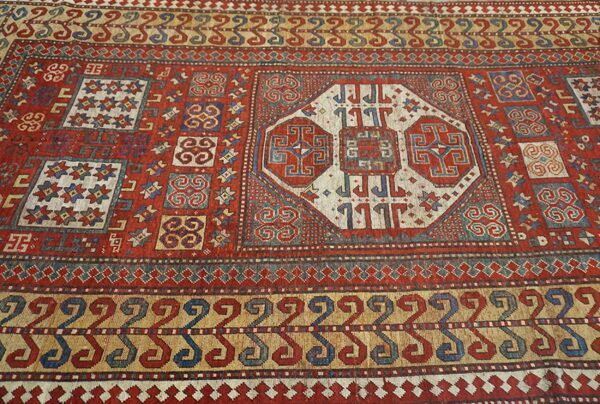 Close-up of a richly colored antique rug featuring geometric motifs in red, blue, and cream by rugs on net. By rugs on net