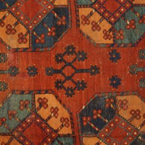 Close-up of a richly colored antique rug featuring geometric medallions in red, orange, blue, and teal by Rugs On Net. by Rugs On Net