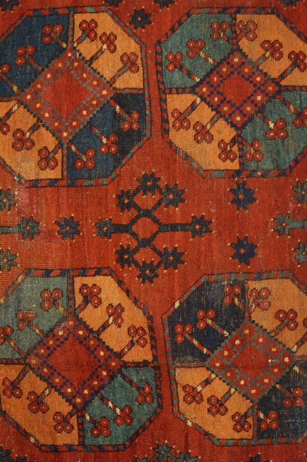 Close-up of a richly colored antique rug featuring geometric medallions in red, orange, blue, and teal by rugs on net. By rugs on net