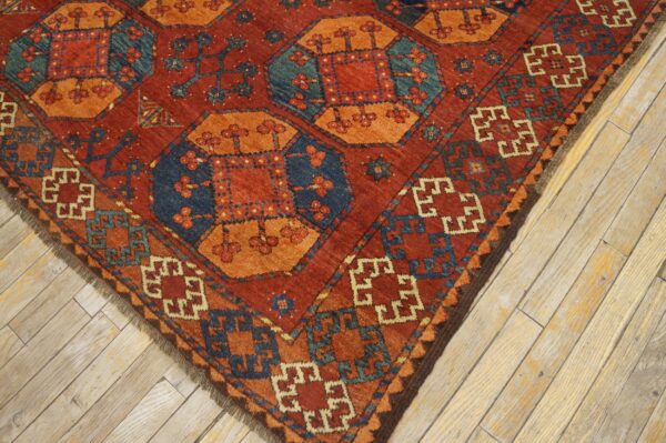 Close-up corner view of a richly colored rug with geometric patterns in red, orange, and blue, by rugs on net. By rugs on net