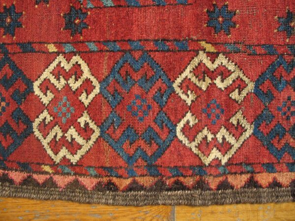 Close-up of geometric patterns in red, blue, and cream on an antique rug by rugs on net. By rugs on net