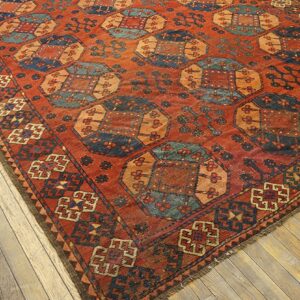 Close-up view of a richly colored, geometric rug with terracotta, blue, and orange tones, on a light wood floor by Rugs On Net