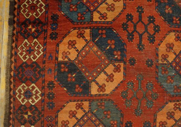 Close-up of a richly colored, geometric patterned rug featuring red, orange, and dark blue tones, by rugs on net. By rugs on net