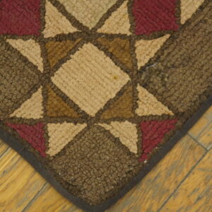Close-up of a hooked rug with a star pattern in brown, tan, and burgundy colors, by Rugs On Net