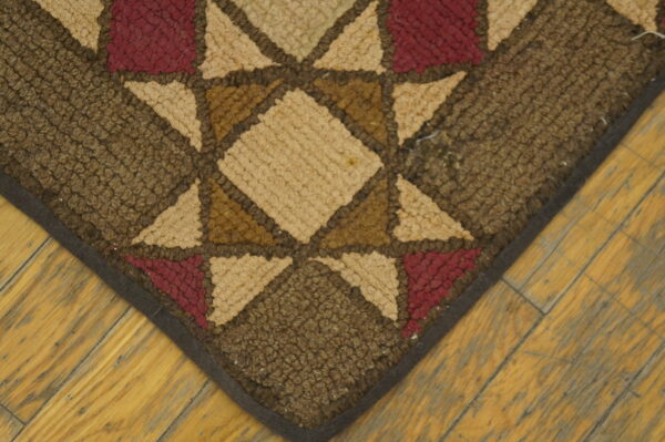 Close-up of a hooked rug with a star pattern in brown, tan, and burgundy colors, by rugs on net