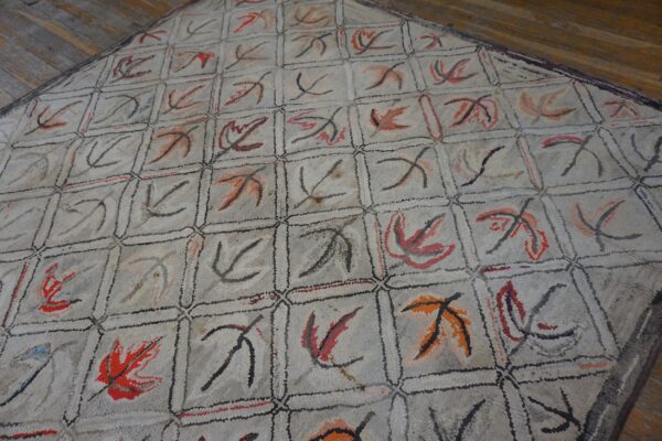 Close-up of a light-colored rug with a grid pattern featuring abstract leaf motifs in red, orange, and black, by rugs on net