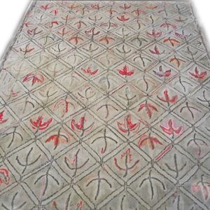 A close-up view of a light-colored rug featuring a repeating diamond lattice pattern with stylized red and black leaf motifs, by Rugs On Net. by Rugs On Net