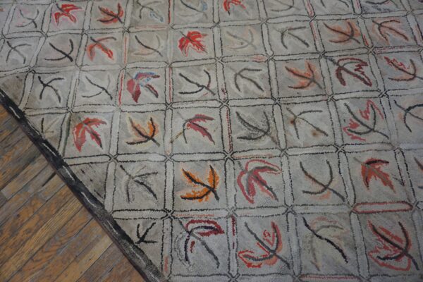 Close-up of a light-colored rug with a grid pattern containing abstract leaf shapes in red, orange, and black, by rugs on net
