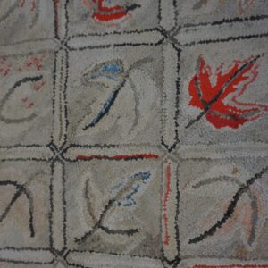 Close-up of a light-colored rug with a grid pattern featuring abstract leaf motifs in red, blue, and gray, by Rugs On Net