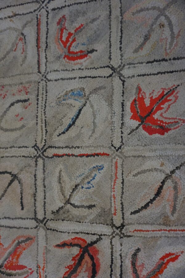 Close-up of a light-colored rug with a grid pattern featuring abstract leaf motifs in red, blue, and gray, by rugs on net