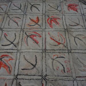 Close-up of a light-colored rug with a grid pattern featuring abstract red and black leaf shapes, by Rugs On Net