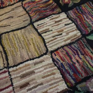 Close-up of a colorful, patchwork hooked rug with varied textures and floral accents by Rugs On Net. by Rugs On Net