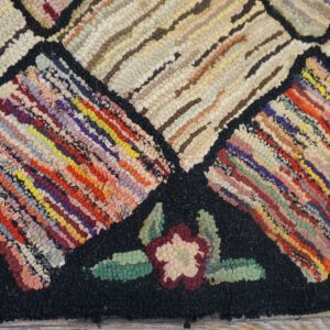 Close-up of a colorful hooked rug pattern with geometric shapes and floral accents on a black background, by Rugs On Net