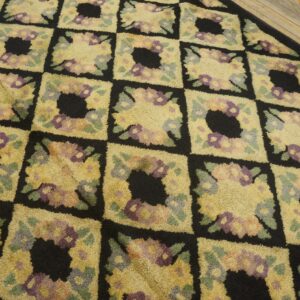 Close-up of a geometric floral rug pattern with yellow, purple, and green accents on a black background, by Rugs On Net